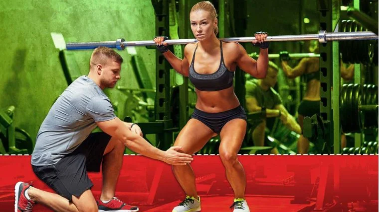 A strength coach prevents an athlete from squatting deep in the gym.
