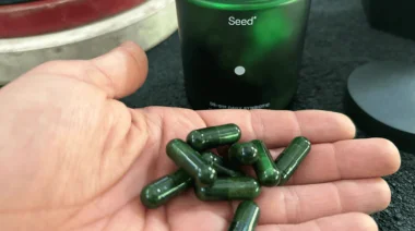 A person holding a handful of Seed Daily Synbiotic capsules.