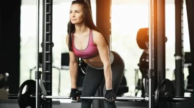 A person in purple sports bra doing a smith machine deadlift.