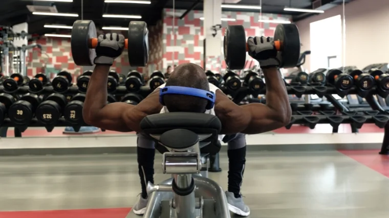 A person doing dumbbell presses on an inclined bench.