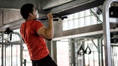 A person performs a chest to bar pullup in the gym.