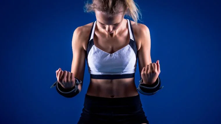 An athletic person with weights wrapped around their wrists.