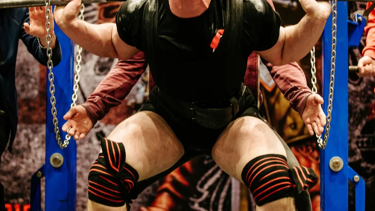 man performs powerlifting squat 