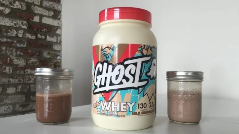 Two shakes next to a container of Ghost Whey Protein.