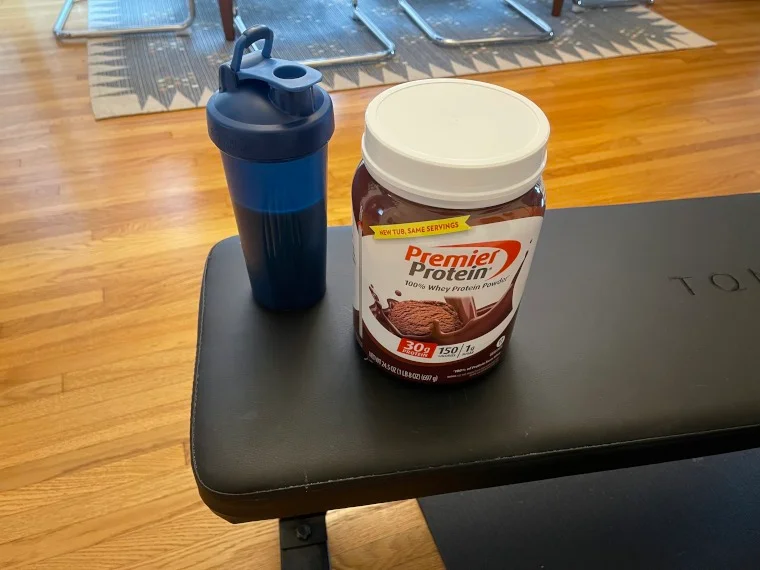 A Premier Protein Powder shake on a weight bench.
