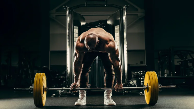 A person trying to lift a barbell off the floor.