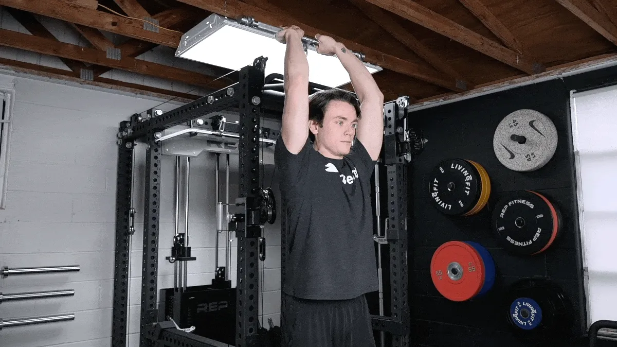 A person performing the cable overhead triceps extension.