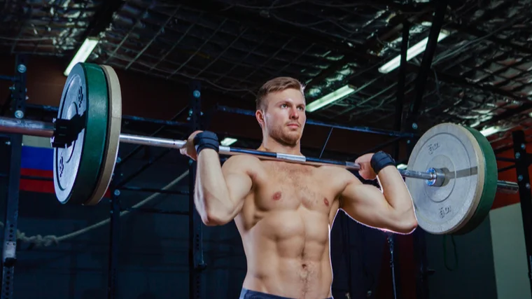man holds a barbell on shoulders 