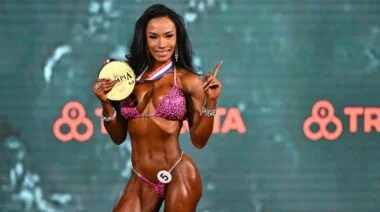 Bikini competitor holding up her 2022 gold medal for the 2022 Olympia.