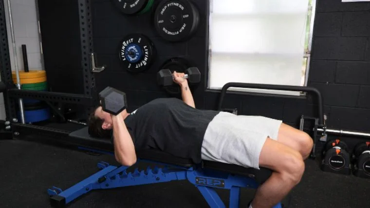 BarBend's Jake Herod performing the dumbbell bench press exercise.