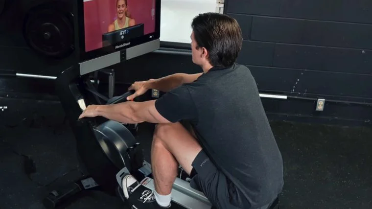 A person exercising on a rowing machine. 