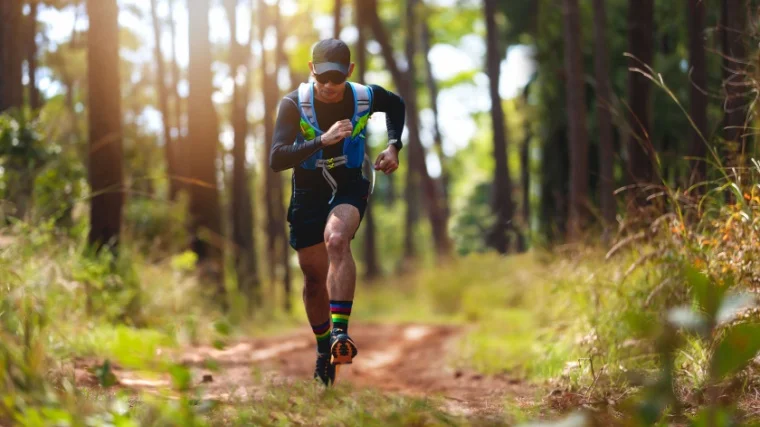 A person running on a trail in a woody area.