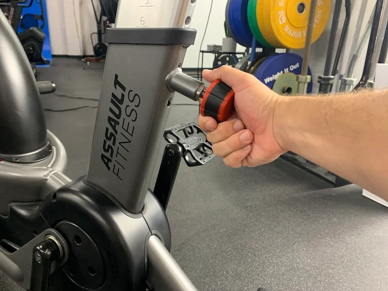 a person adjusting the seat height of the Assault Fitness AirBike Elite.