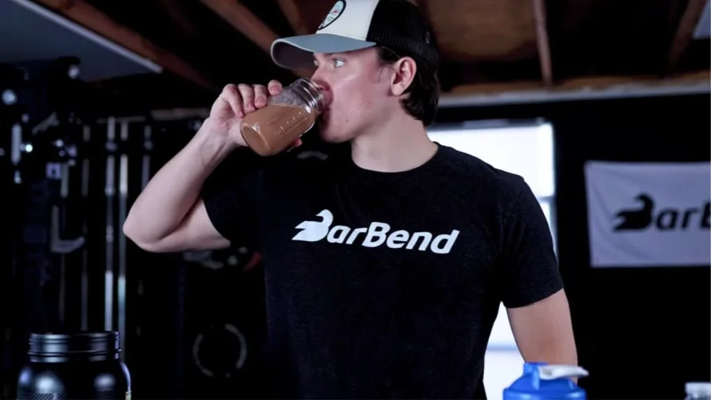 A person drinking a protein powder shake from a glass.
