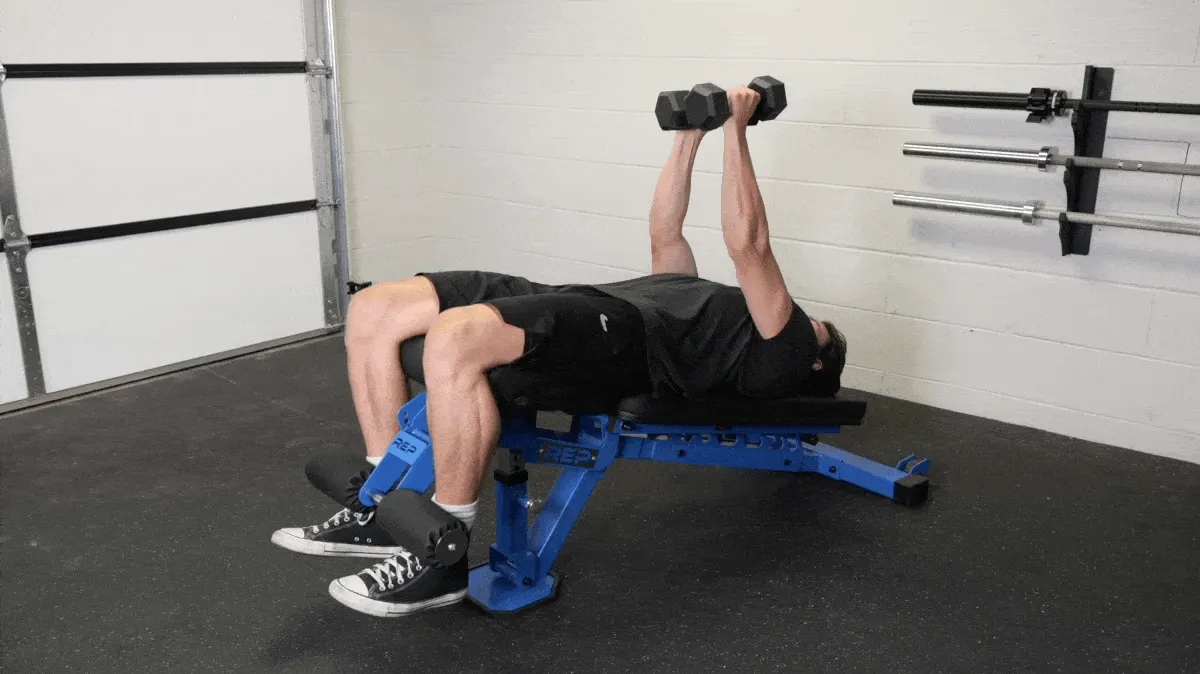 A person in a grey t-shirt and black shorts performs the dumbbell flye on a blue decline bench.