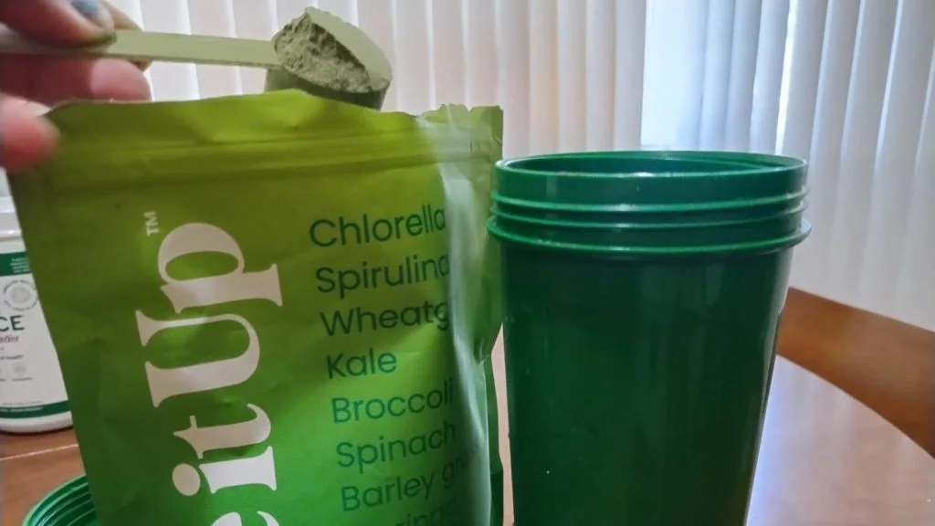 Our tester lifts a scoop of Live It Up Greens from the bag. Our tester lifts a scoop of Live It Up Greens from the bag.