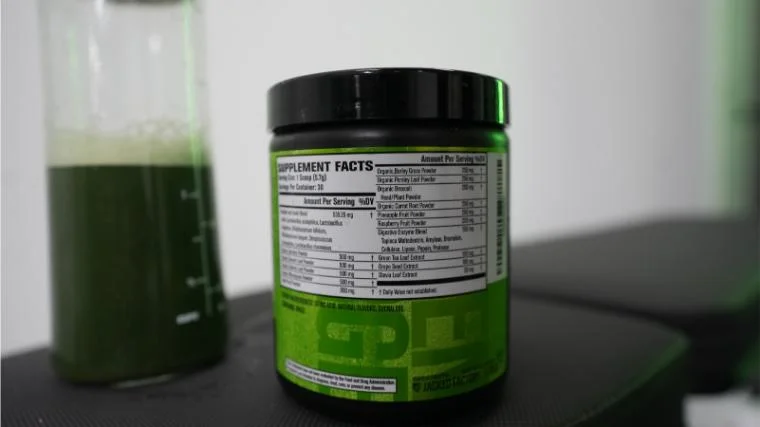 Jacked Factory Greens Surge on a bench in the BarBend gym.
