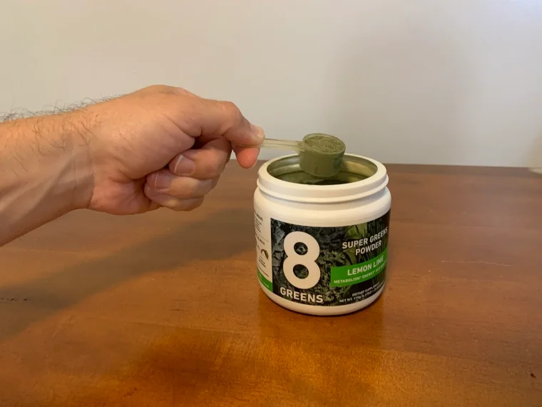 Our tester holds a scoop of 8Greens Super Greens Powder.