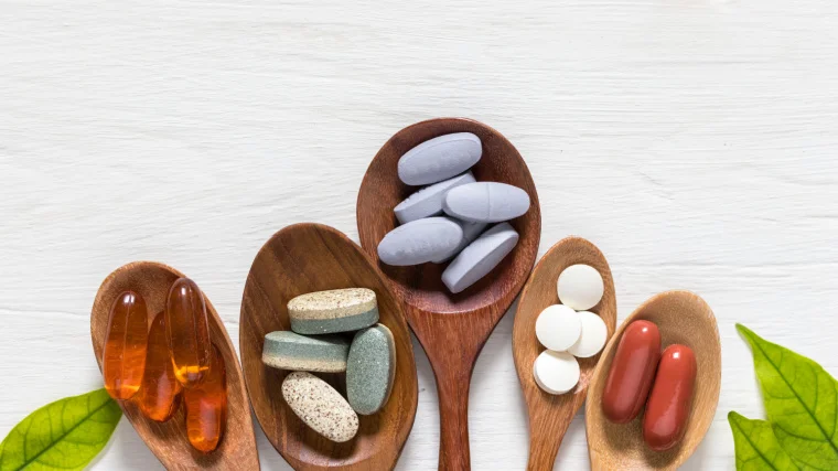 a variety of different supplement pills on spoons