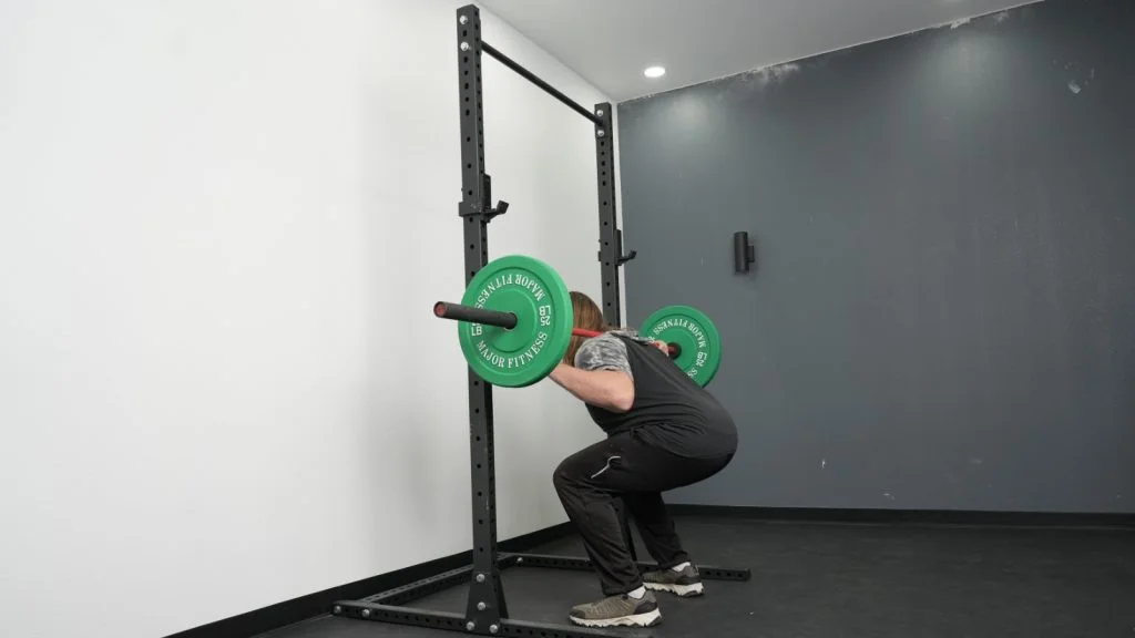 fringe-sport-unlimited-squat-pullup-rack-side-full-view-squat A person squatting with the Fringe Sport Unlimited Squat Stand with Pull-Up Bar.